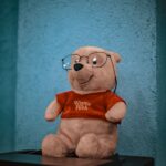 Cute Winnie the Pooh stuffed toy wearing glasses, ideal for nostalgic and playful themes.
