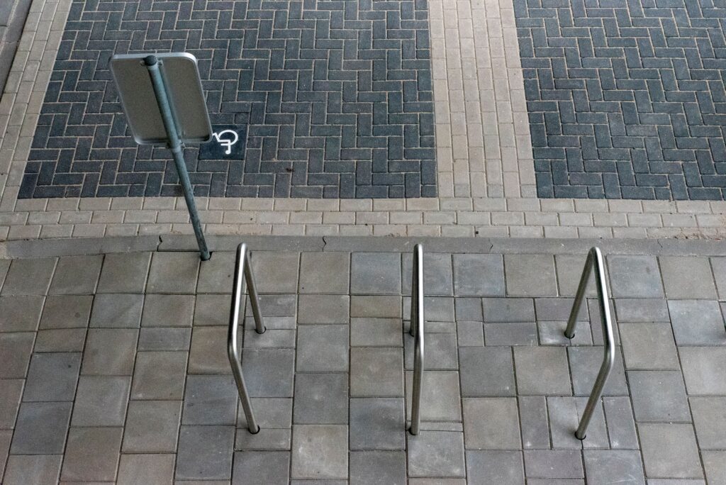 pexels-photo-34433498-34433498 A top view of a bicycle stand and paved sidewalk with a street sign.